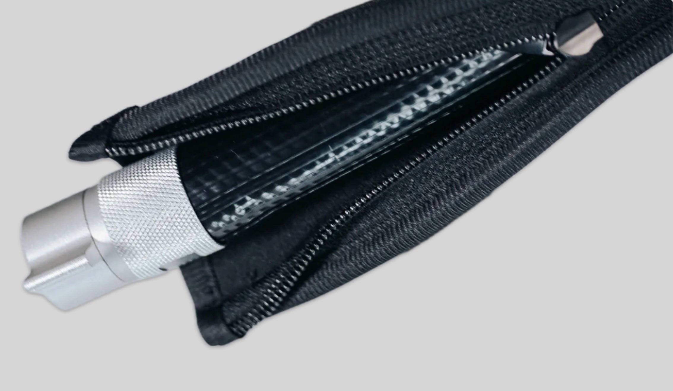 A close-up of a black zippered pouch with a silver metal cylindrical tool partially pulled out, set against a plain light gray background.